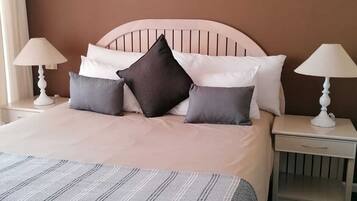 A neatly made bed with a striped bedspread, two bedside tables with lamps, and two framed pictures on the wall.