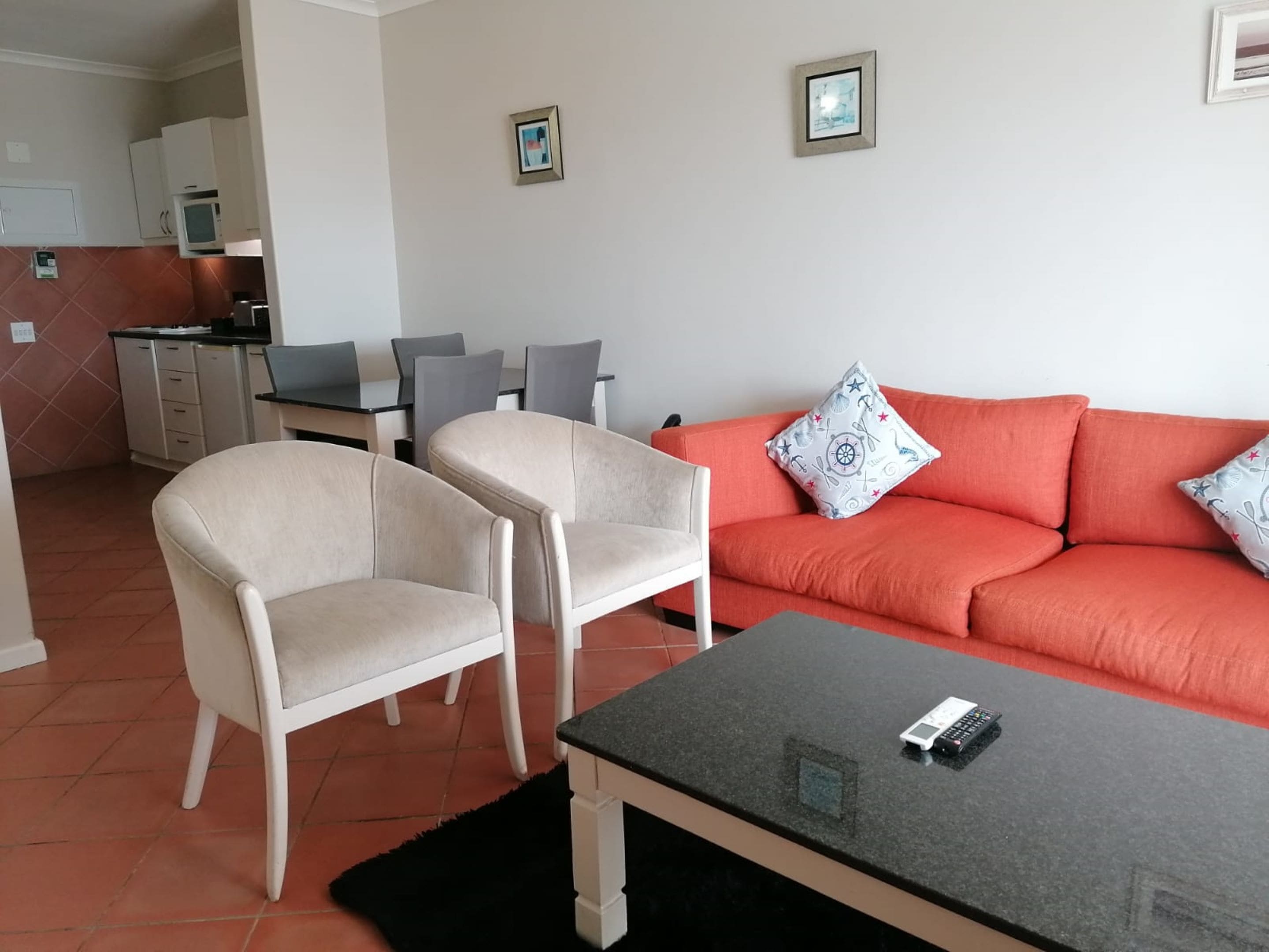 A living room with a sofa, two armchairs, a coffee table, and a dining area with a table and chairs.