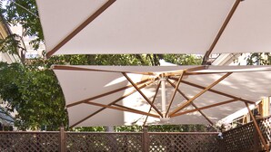 An outdoor patio with white wicker furniture, a table with drinks and snacks, and a wooden fence in the background. - Hotel Best Roma (Rome)