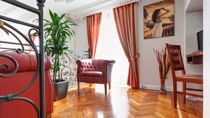 A room with a wooden parquet floor, a red upholstered armchair, a potted plant, and a painting on the wall. - Hotel Best Roma (Rome)