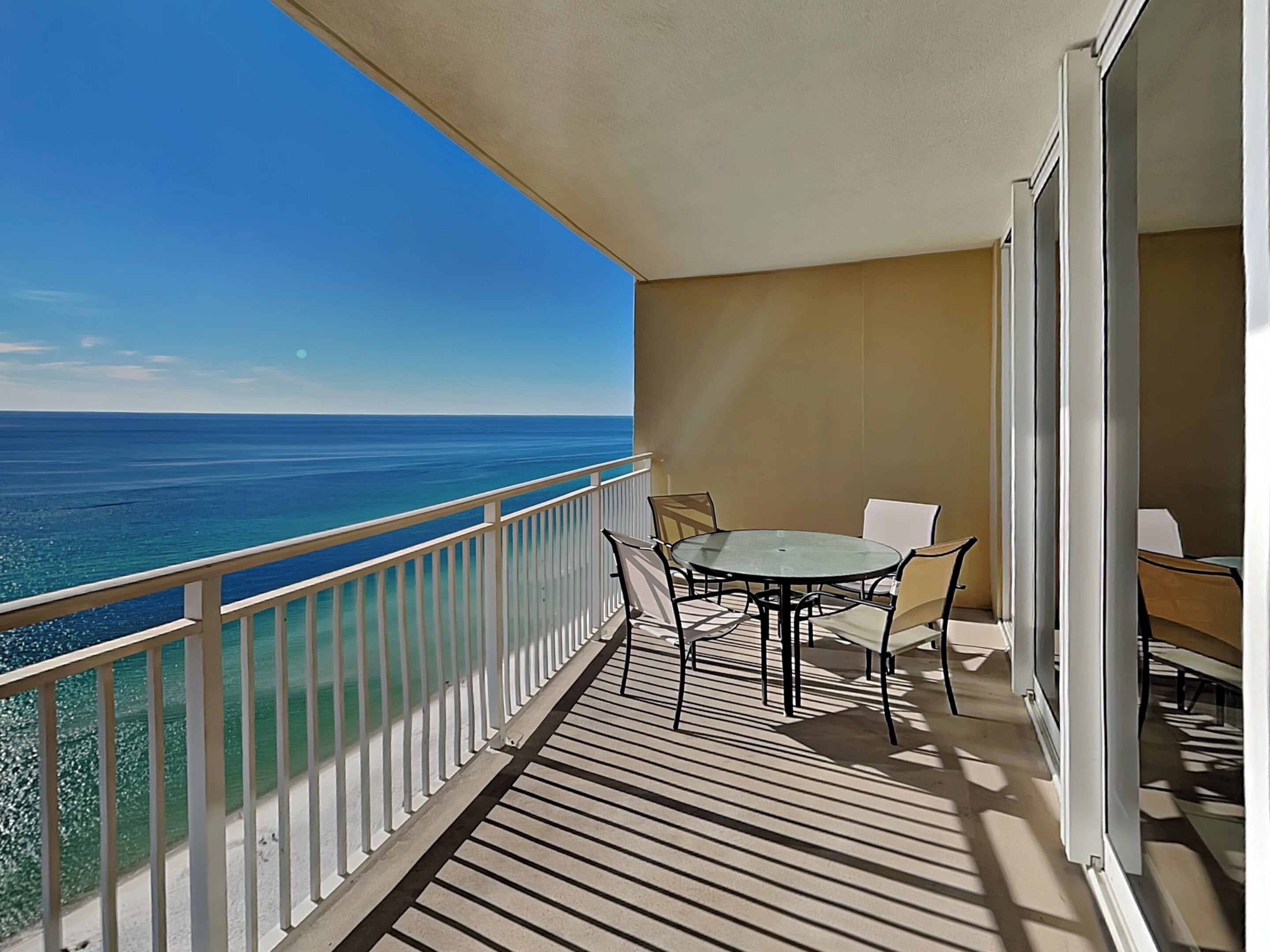 Un balcon avec une table et des chaises, donnant sur une mer d’un bleu limpide.