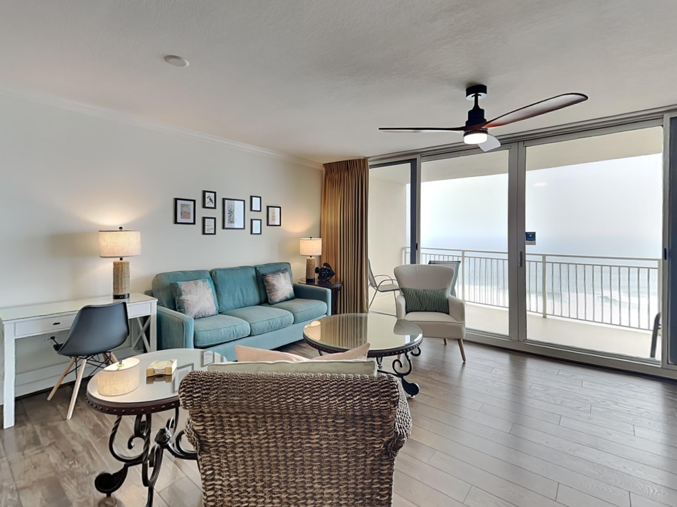 A modern living room with a sofa, armchairs, a coffee table, and a balcony with a view.