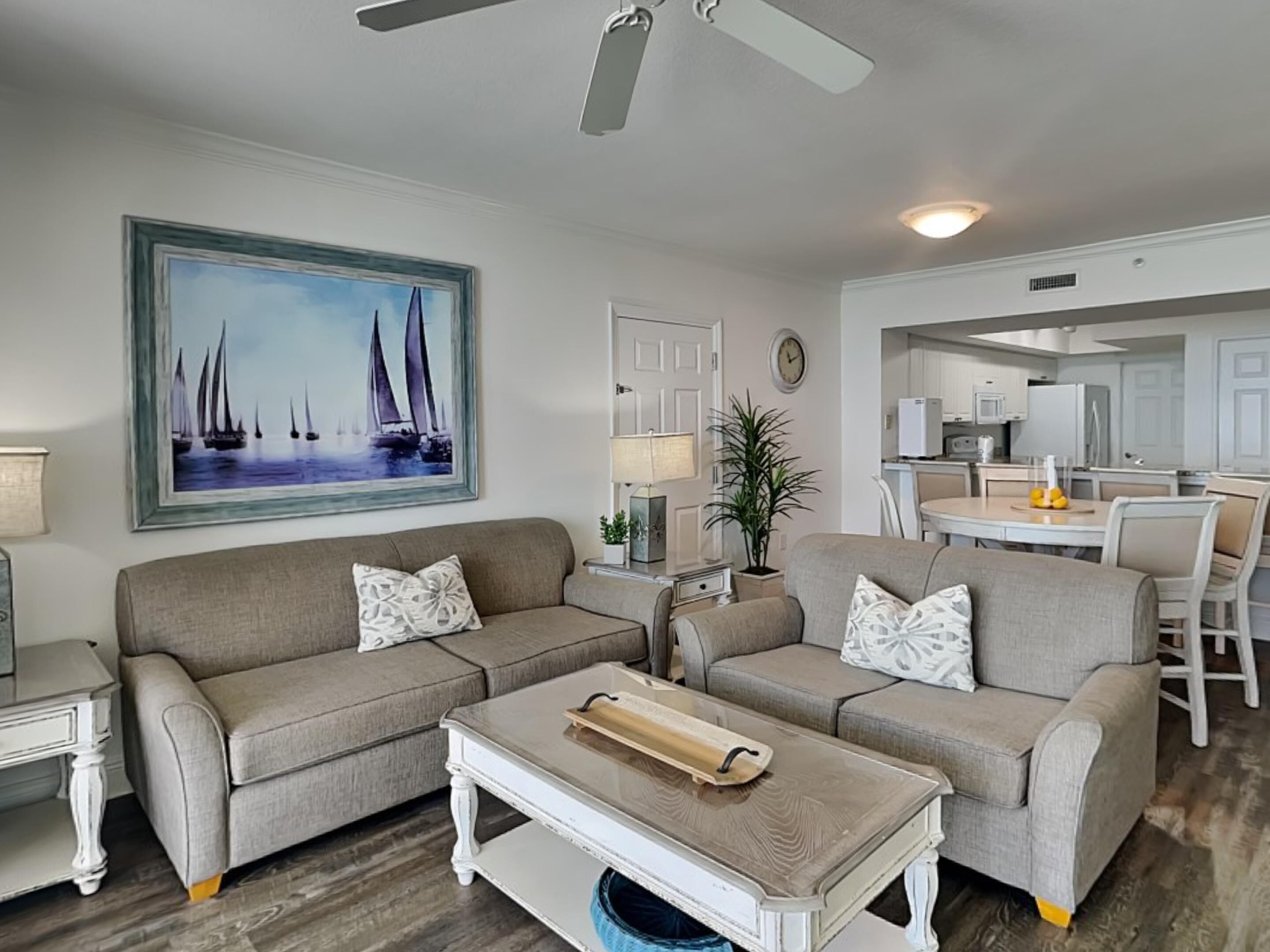 A living room with a sofa, coffee table, and a painting of sailboats.