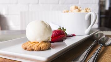 Une assiette à dessert avec une boule de glace, un biscuit et une fraise, le tout présenté sur une assiette blanche.