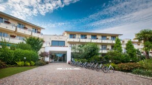 A hotel with a stone-paved entrance, a row of bicycles, and lush greenery.