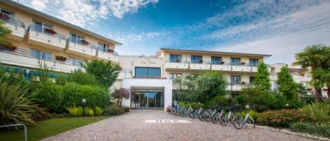 A hotel with a stone-paved entrance, a row of bicycles, and lush greenery.