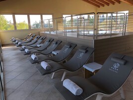 Una fila de tumbonas con toallas, zona de piscina y vistas al exterior.