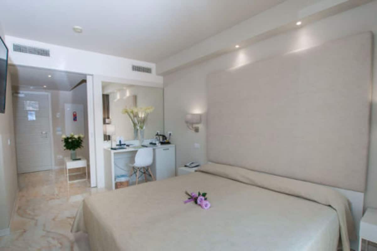 A hotel room with a bed, a desk, and a chair.