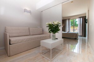 Una sala de estar moderna con un sofá color beige, una mesa de centro blanca y un jarrón con flores blancas.