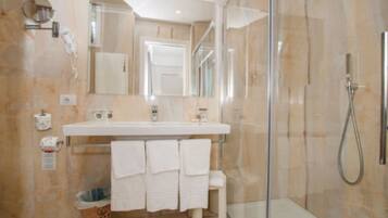 A modern bathroom with a glass-enclosed shower, a white sink, and a large mirror.