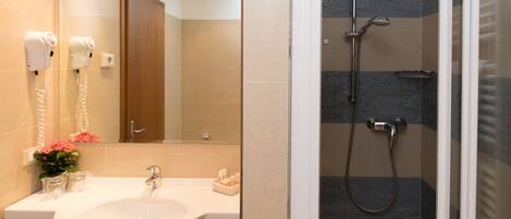 Un baño moderno con lavamanos, espejo, secador de pelo y ducha.