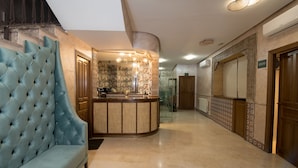 A lobby with a tufted blue sofa, a reception desk, and patterned walls. - Hotel Sol (Toledo)