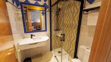 A bathroom with a glass-enclosed shower, a sink, and a toilet.
