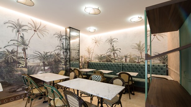 A restaurant with a tropical mural, green cushioned seating, and a mix of wooden and wicker chairs. - Hotel Sol (Toledo)