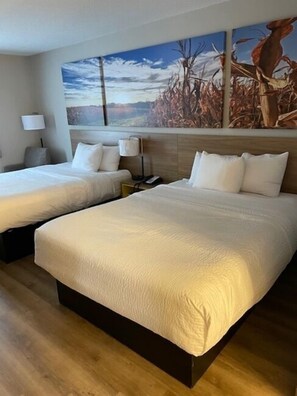 Une chambre d’hôtel avec deux lits, un grand tableau au mur et un plancher en bois.