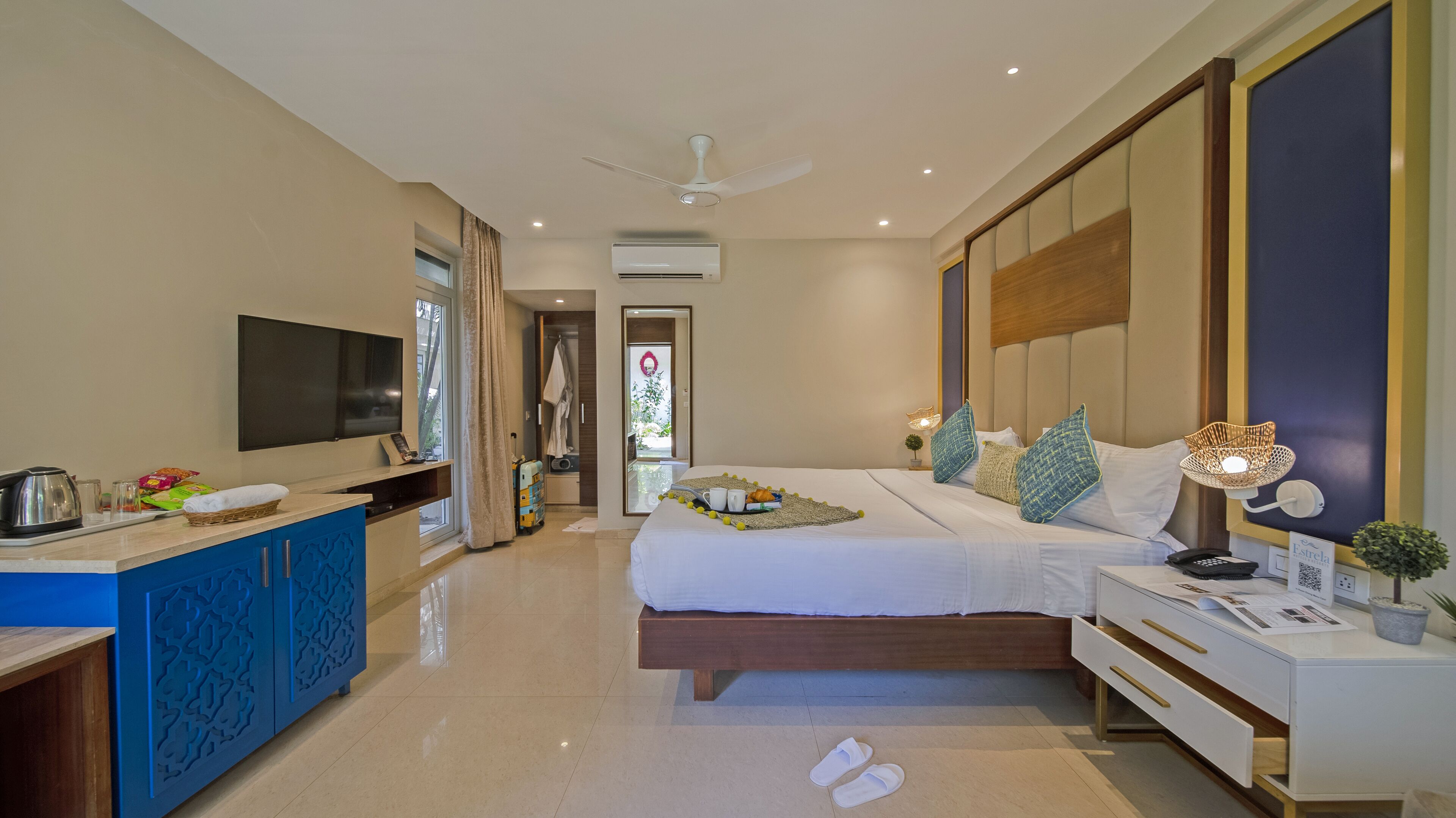 A modern hotel room with a bed, bedside table, TV, and a view of the outside.