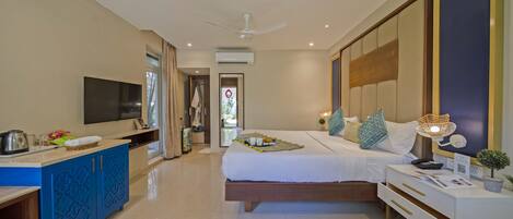 A modern hotel room with a bed, bedside table, TV, and a view of the outside.