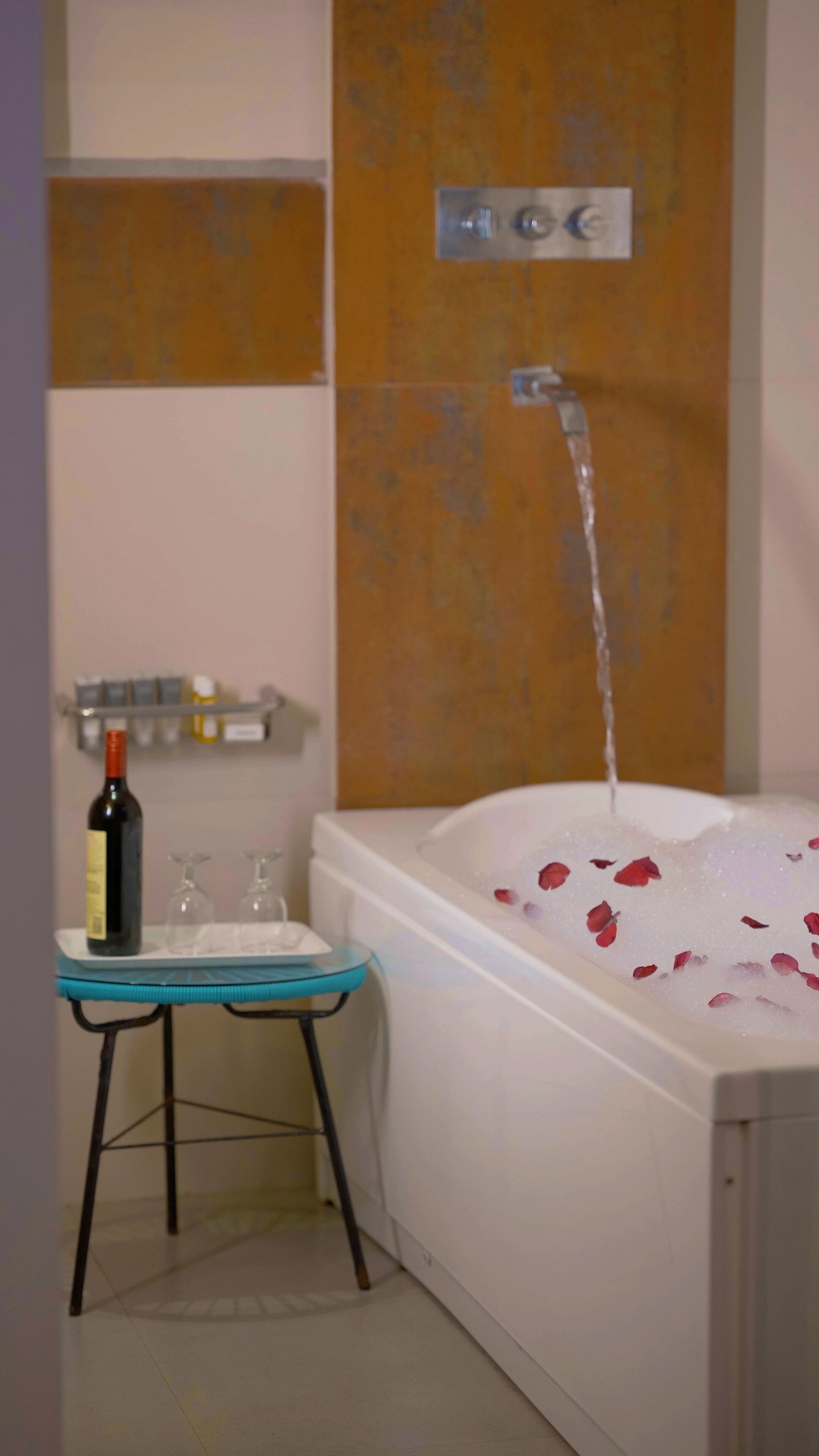A bathroom with a bathtub, a sink, and a wine bottle on a small table.