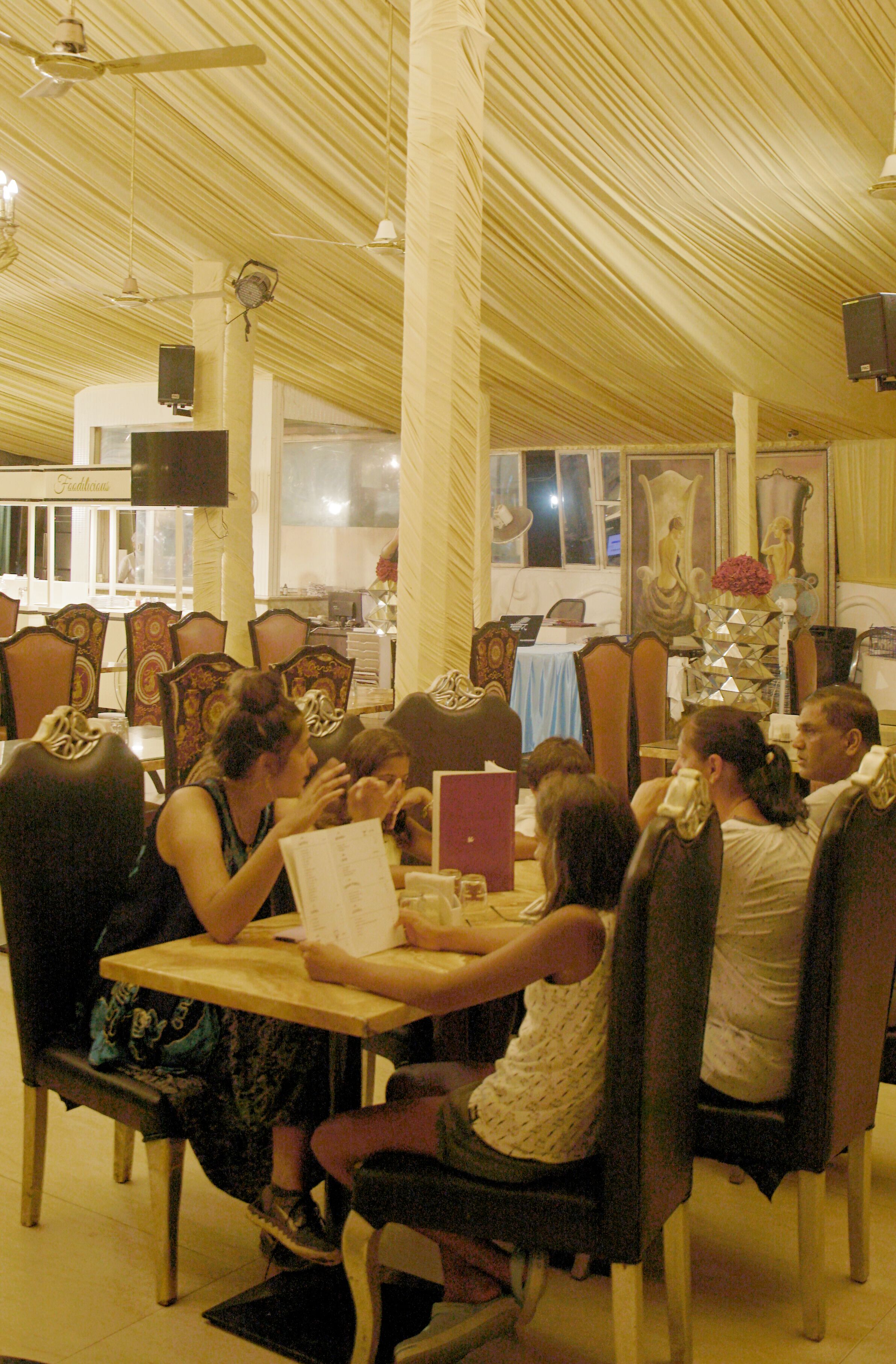A restaurant with wooden ceiling beams, tables with chairs, and a menu on the table.