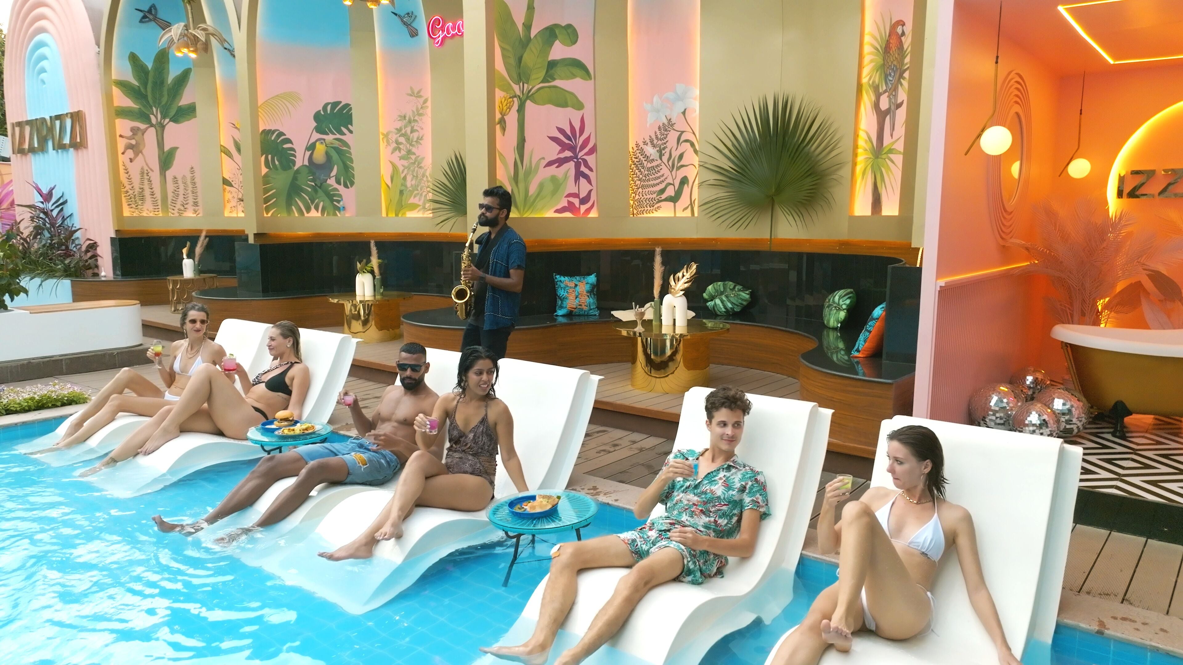 A poolside area with lounge chairs, a bar, and tropical-themed wall art.