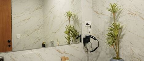 Un baño moderno con pared de mármol, encimera negra, lavabo blanco y espejo.