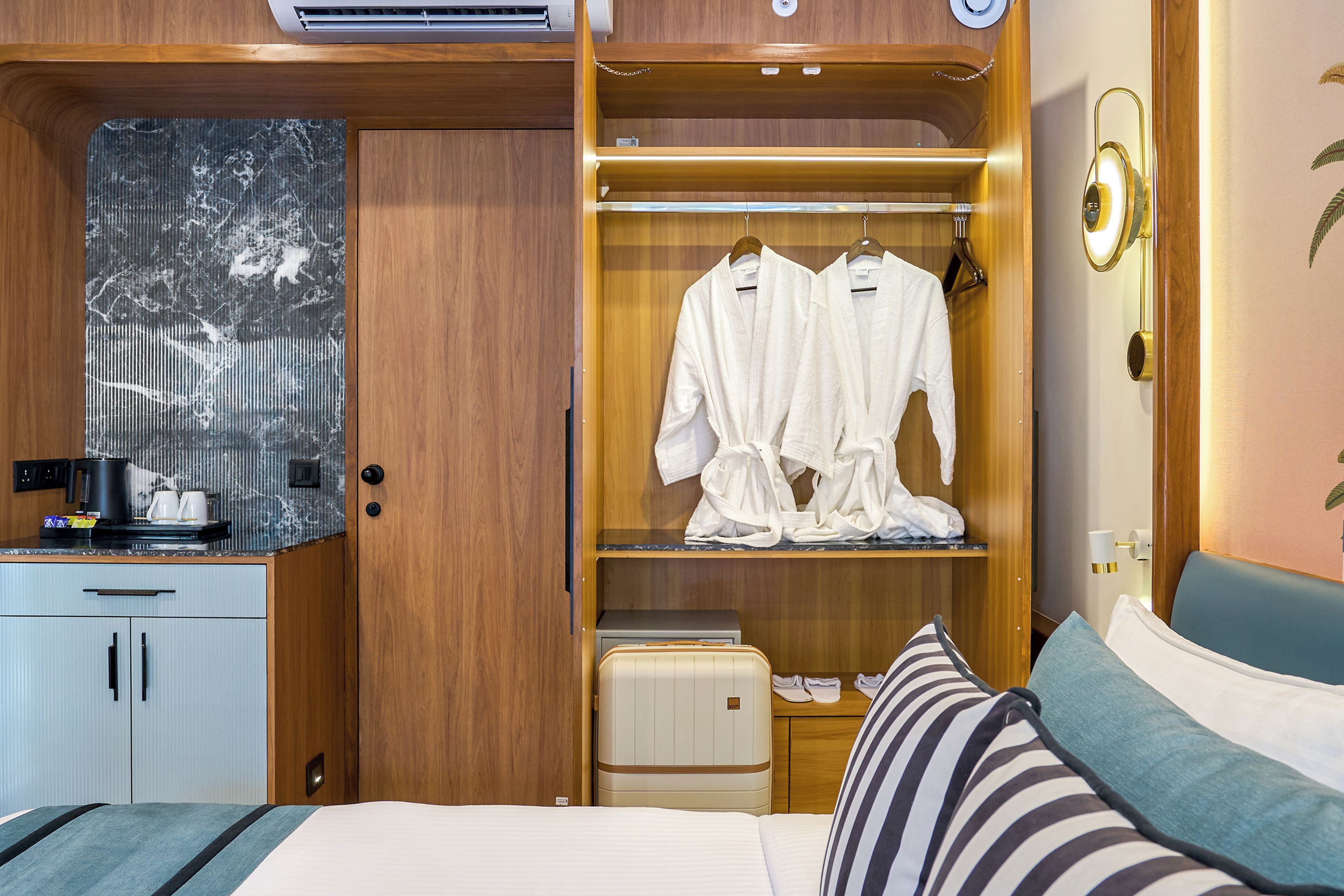 Una habitación de hotel con cama, mesita de noche, armario y espejo.