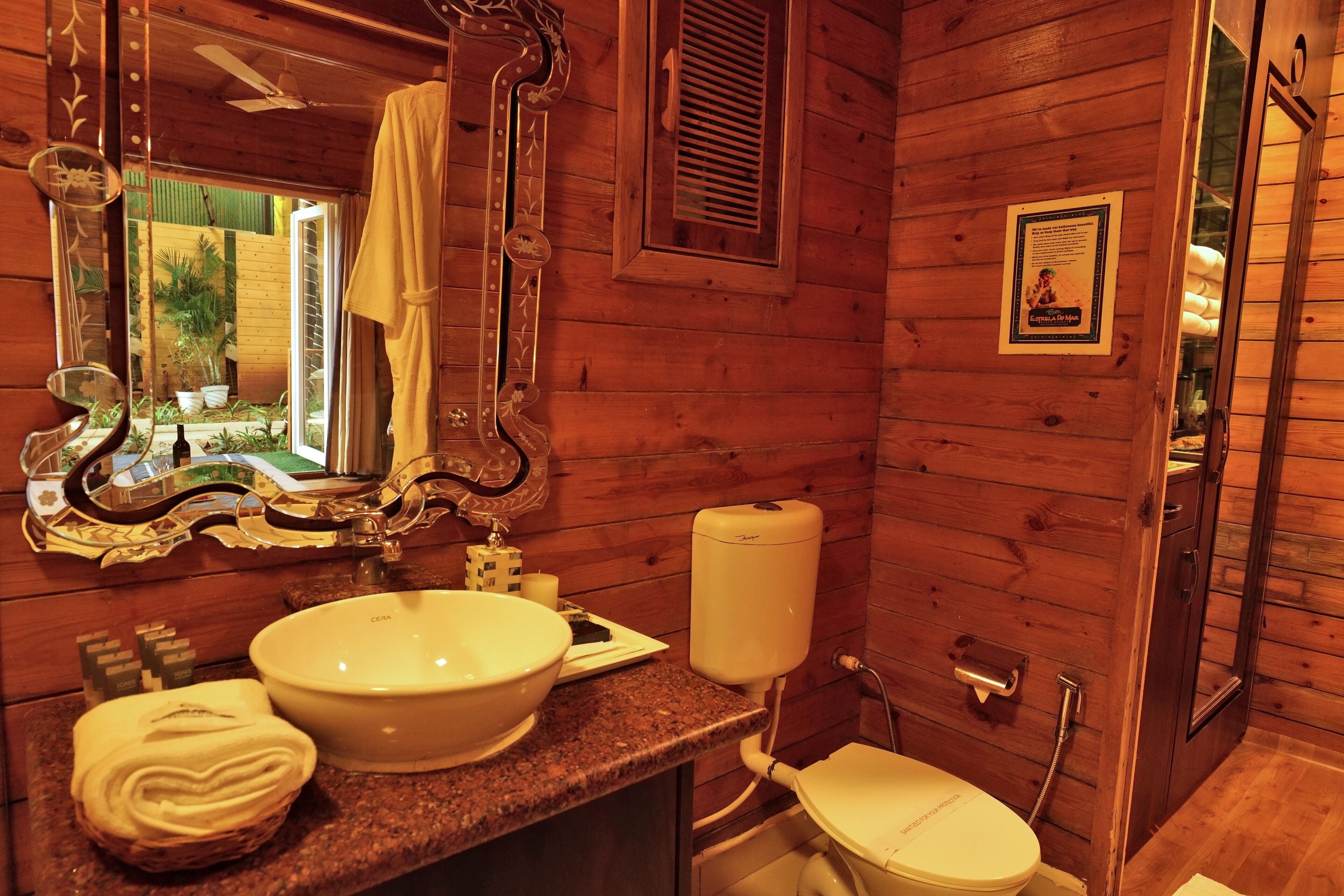 Ein Badezimmer aus Holz mit einem großen Spiegel, einem Waschbecken und einer Toilette.