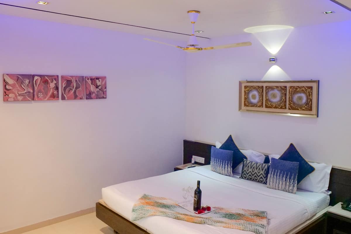 A modern bedroom with a bed, artwork, and ceiling lights.