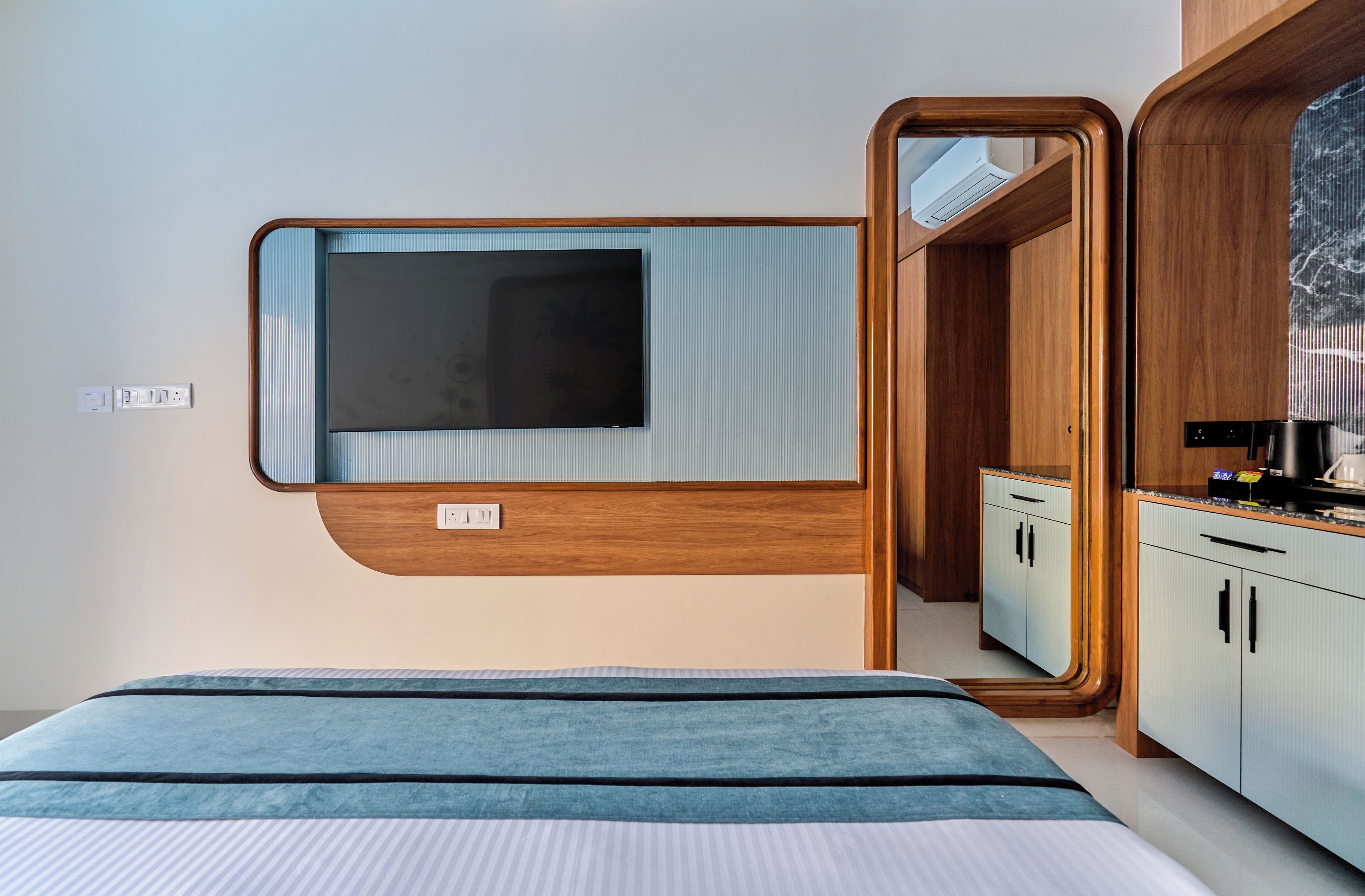A modern bedroom with a bed, a built-in TV, and a wooden wardrobe.