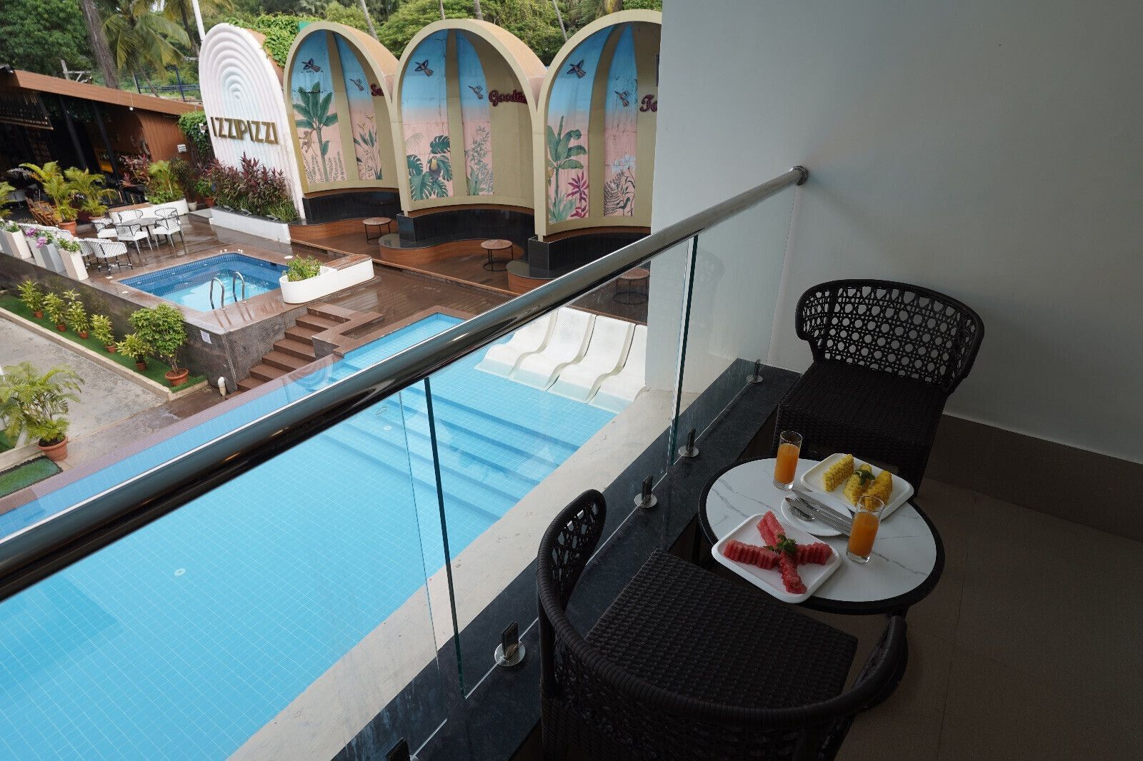 A balcony with a pool view, a table with food, and a sign reading "IZIPIZZA".
