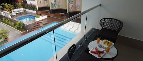 A balcony with a pool view, a table with food, and a sign reading "IZIPIZZA".