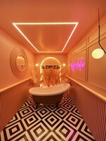 A bathroom with a bathtub, a neon sign reading "ZIPPIZZ", and a neon sign reading "spa".