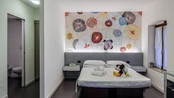 Relax in a stylish room with a large bed, vibrant floral pattern, and a bedside table with a lamp and telephone.