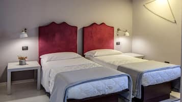 A double room with two beds, each with a red headboard, white bedding, and a bedside table with a lamp.