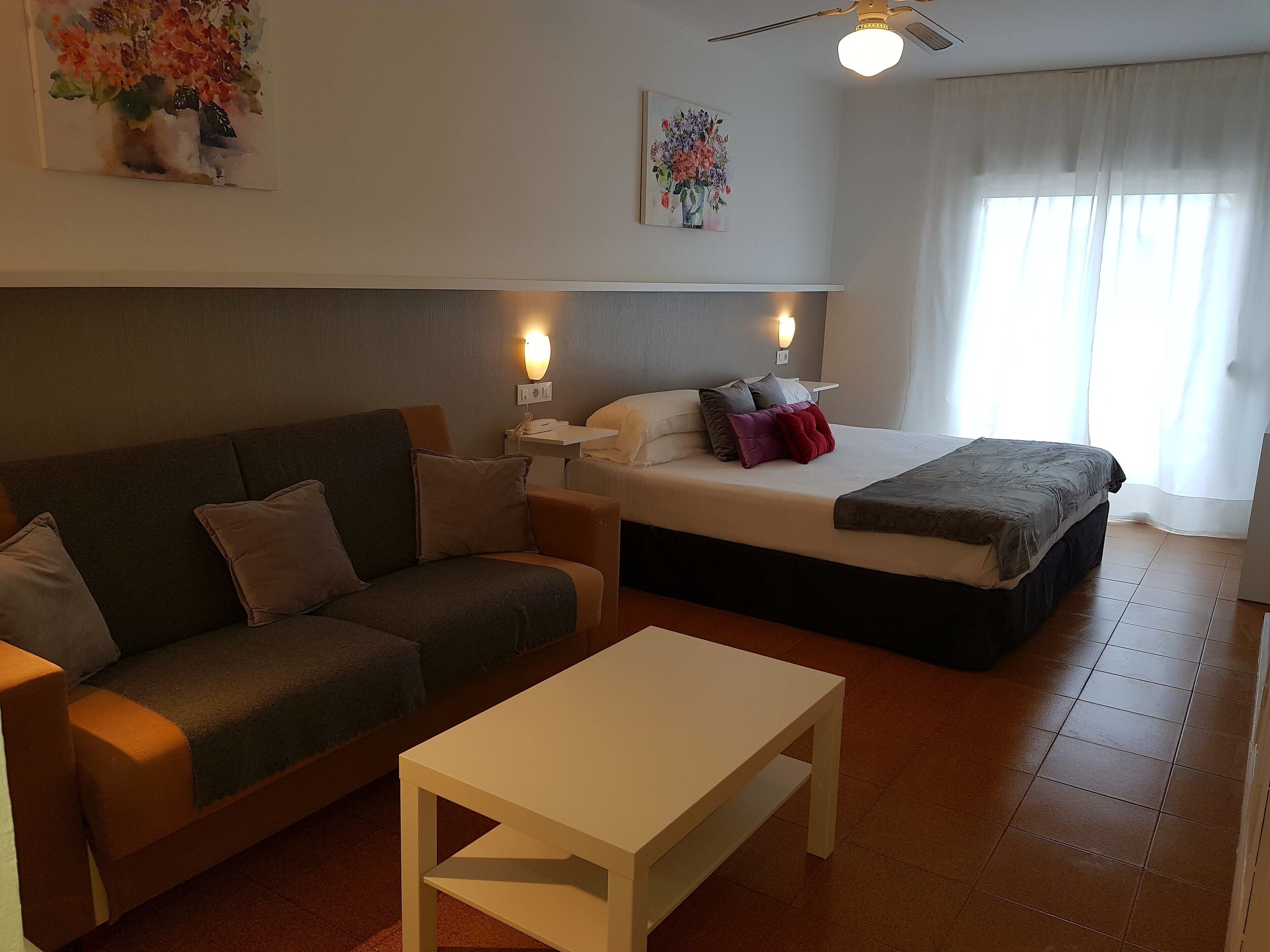 Une chambre d’hôtel moderne équipée d’un canapé, d’un lit, d’une table de chevet et d’une table.