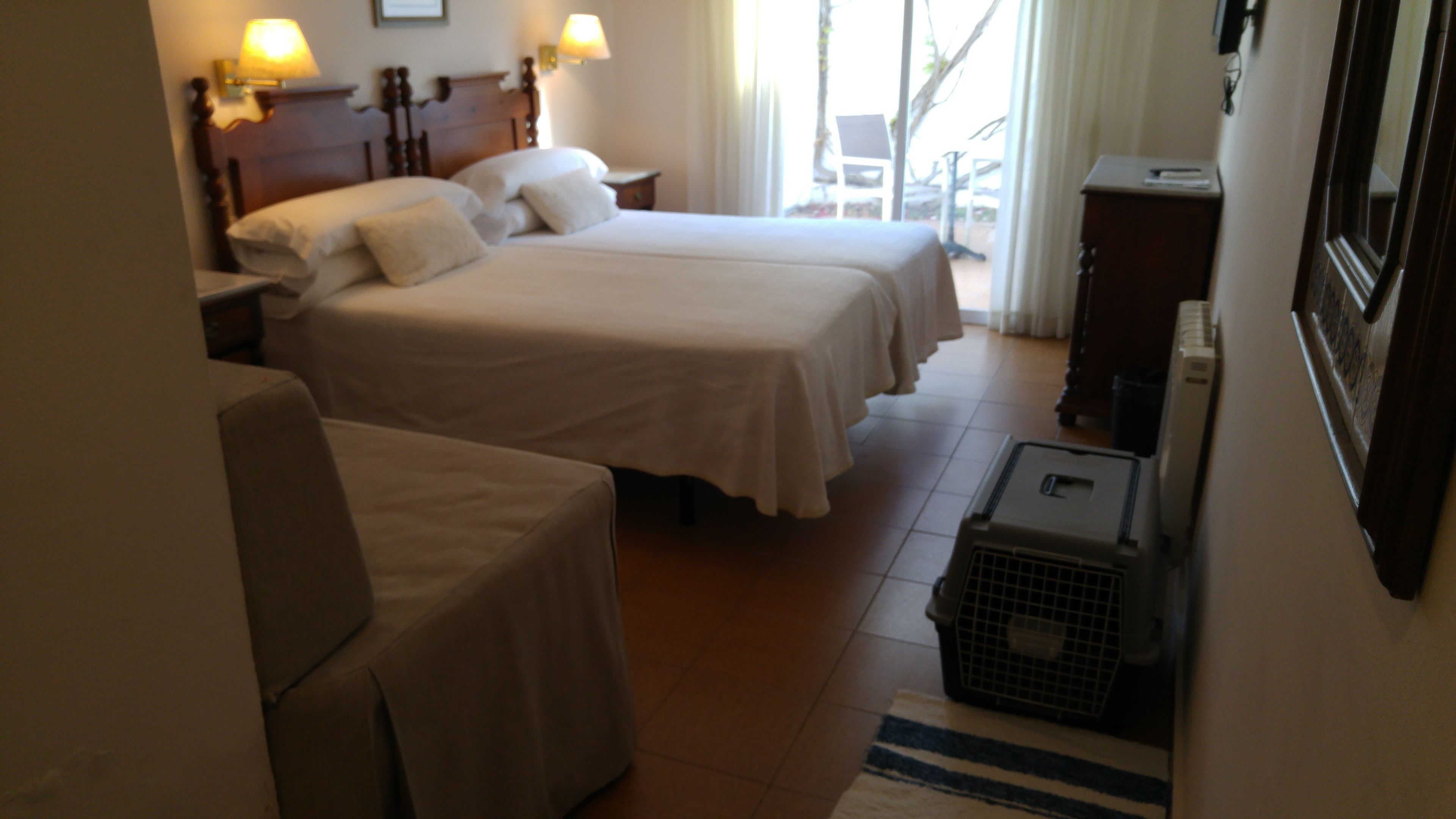 Habitación de hotel con dos camas, una silla, un escritorio y una mesita.