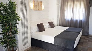 A hotel room with a bed, a potted plant, and a window with curtains. - Hotel Campomar Playa (El Puerto de Santa Maria)