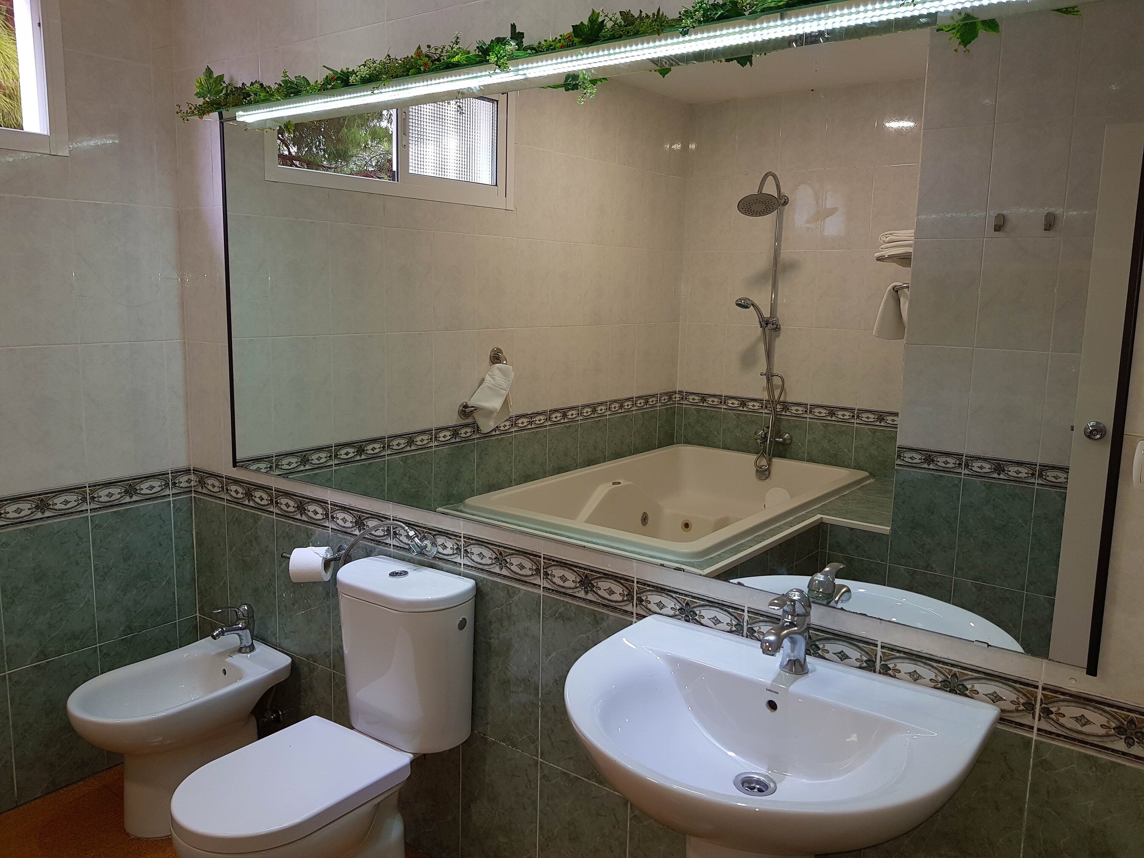 Un baño con bañera, dos inodoros, un bidé y un lavamanos.