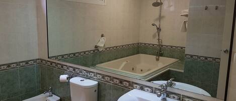 Un baño con bañera, dos inodoros, un bidé y un lavamanos.