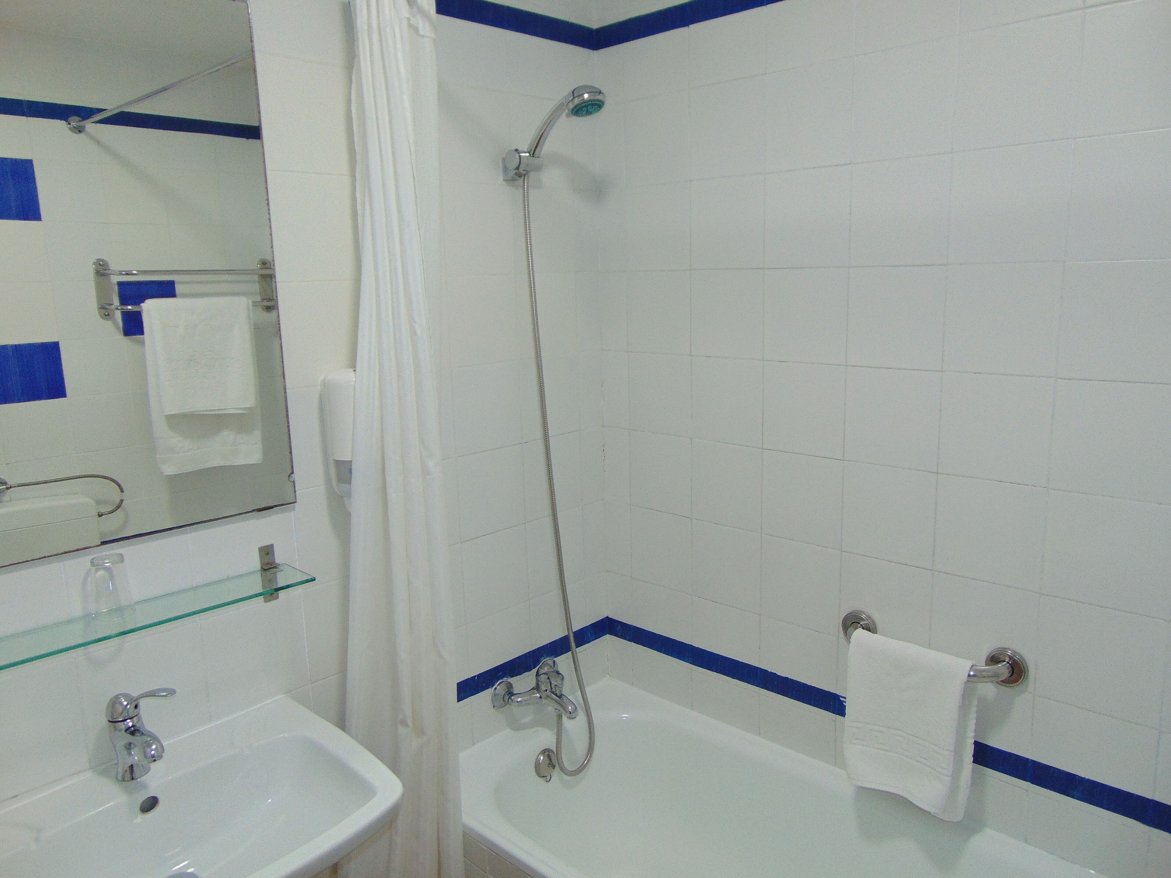 Ein Badezimmer mit Waschbecken, Spiegel, Dusche und Ablagefläche aus Glas.
