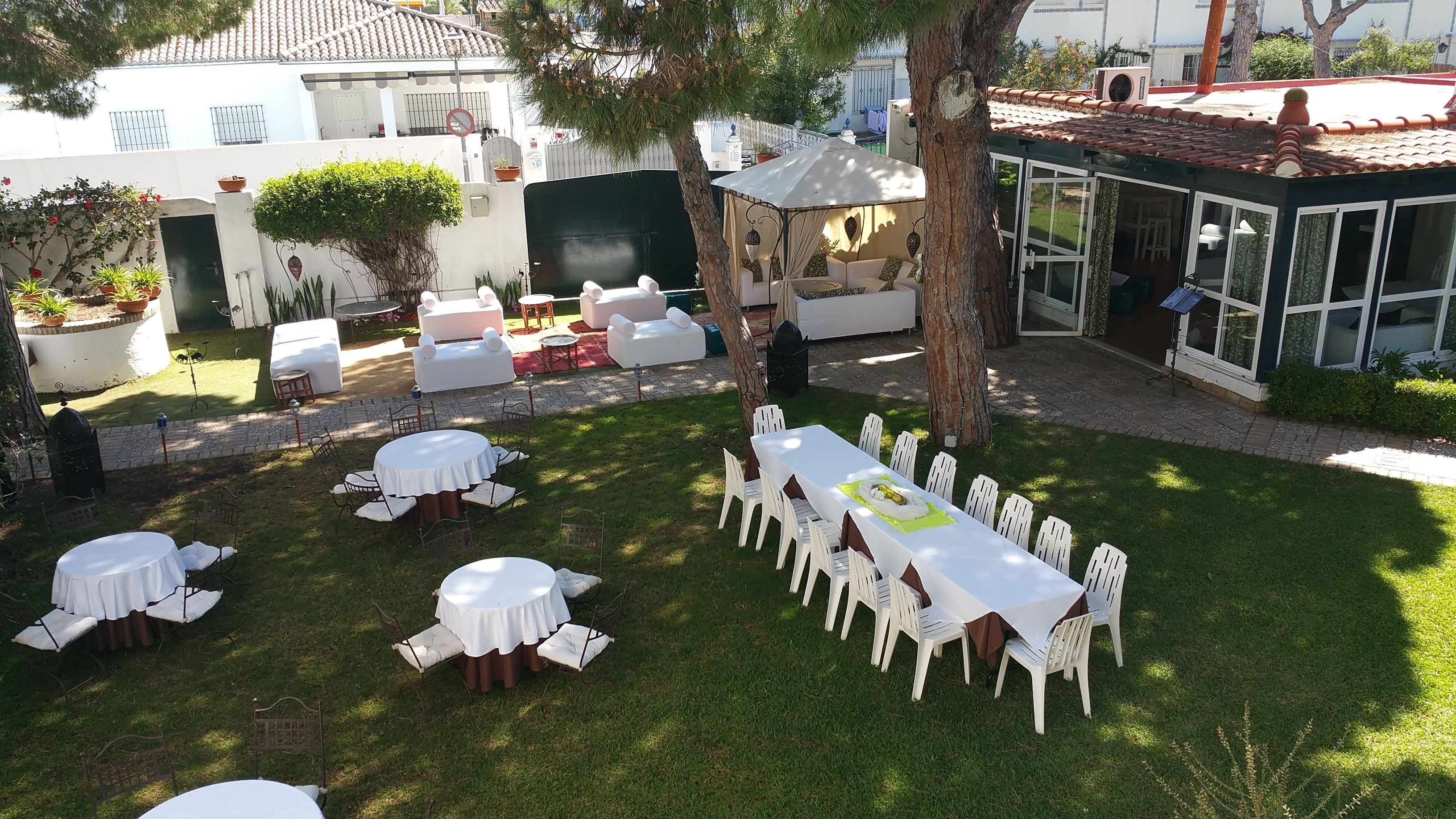 An outdoor patio with round and rectangular tables, white chairs, and a covered seating area.