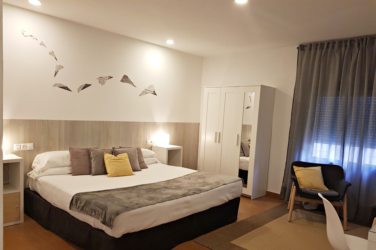 Una habitación de hotel moderna con una cama grande, un escritorio y un armario.