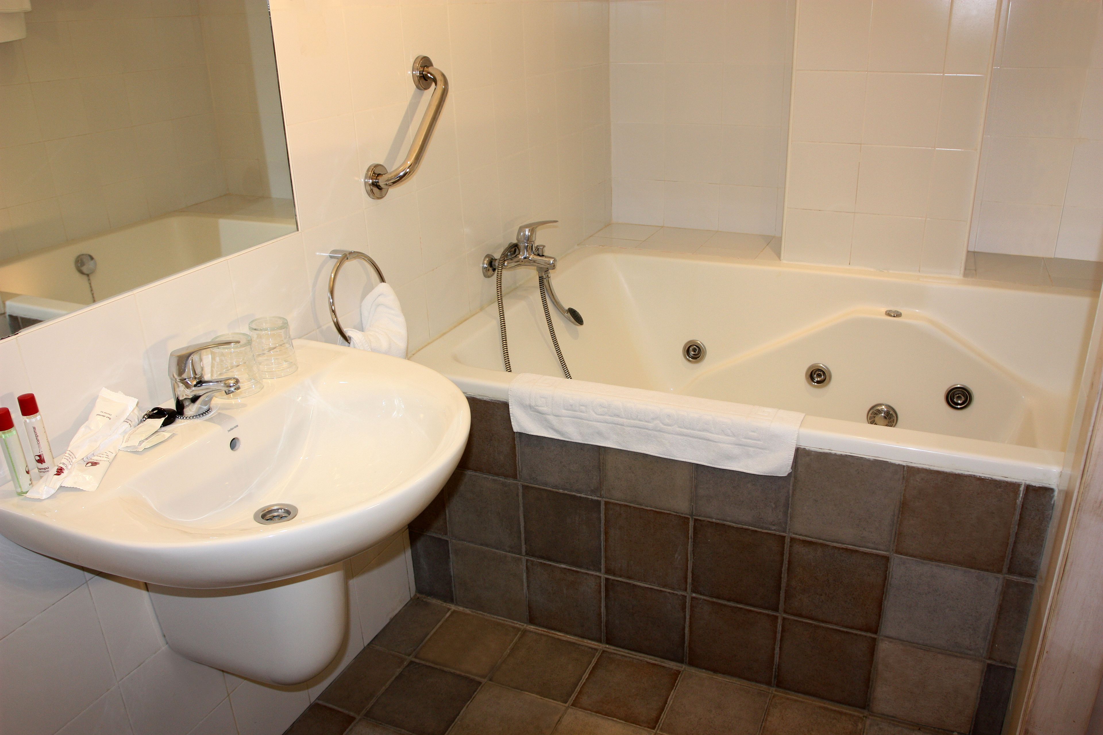 A bathroom with a sink, mirror, and bathtub.