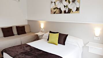 Una habitación de hotel con una cama, un sofá y una mesita de noche con una lámpara.