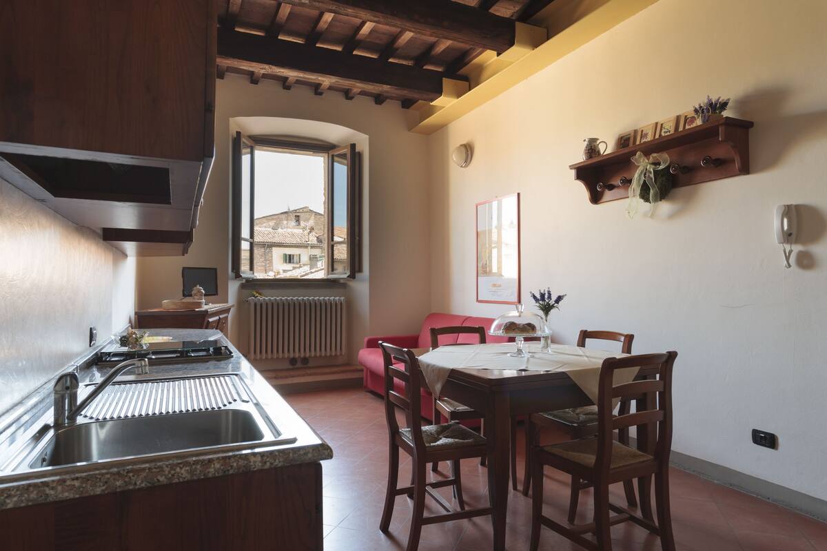 A kitchen with a sink, wooden cabinets, and a dining area with a table and chairs.