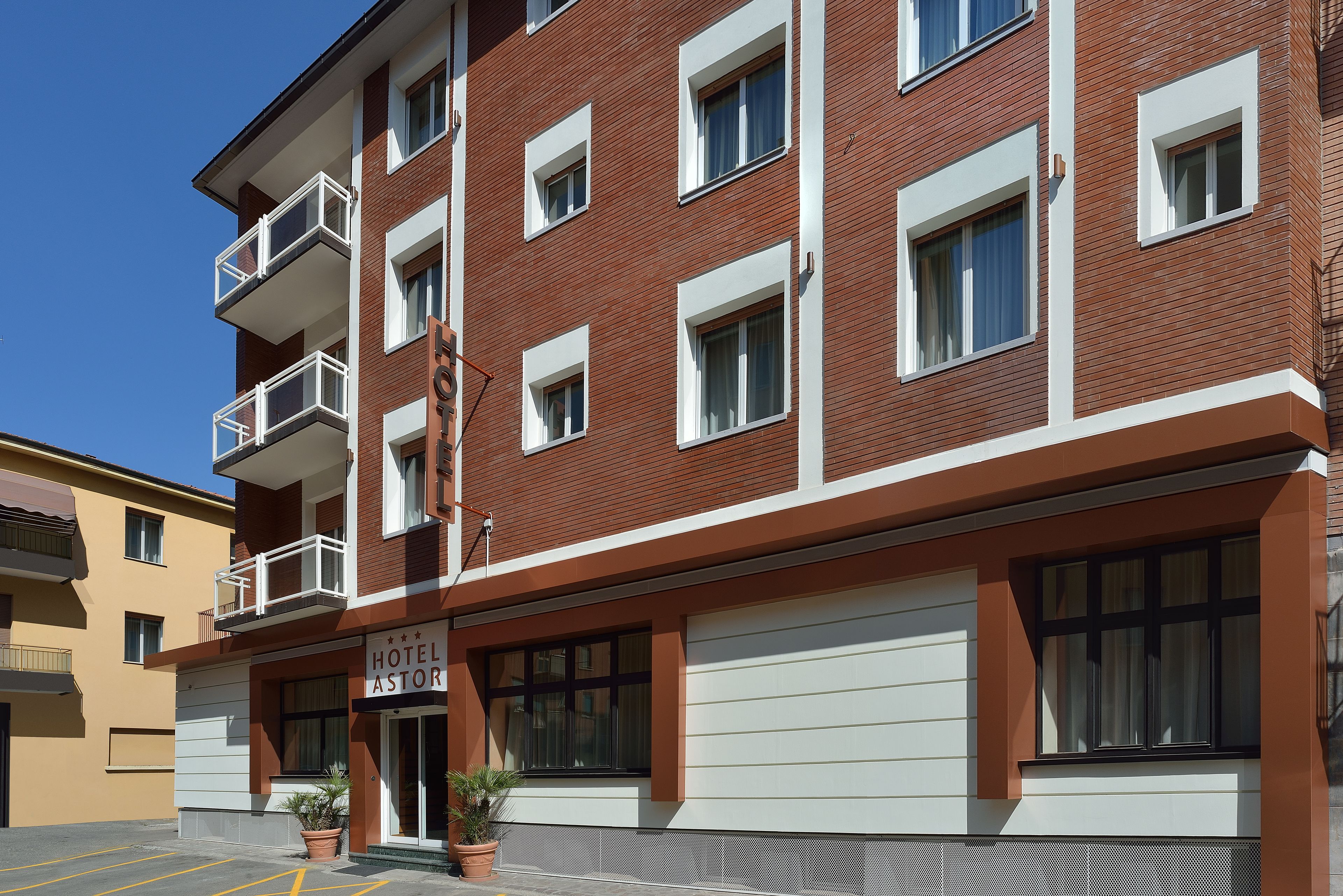 Un hôtel à plusieurs étages, doté d’une façade en briques rouges, de fenêtres à encadrement blanc et de balcons.