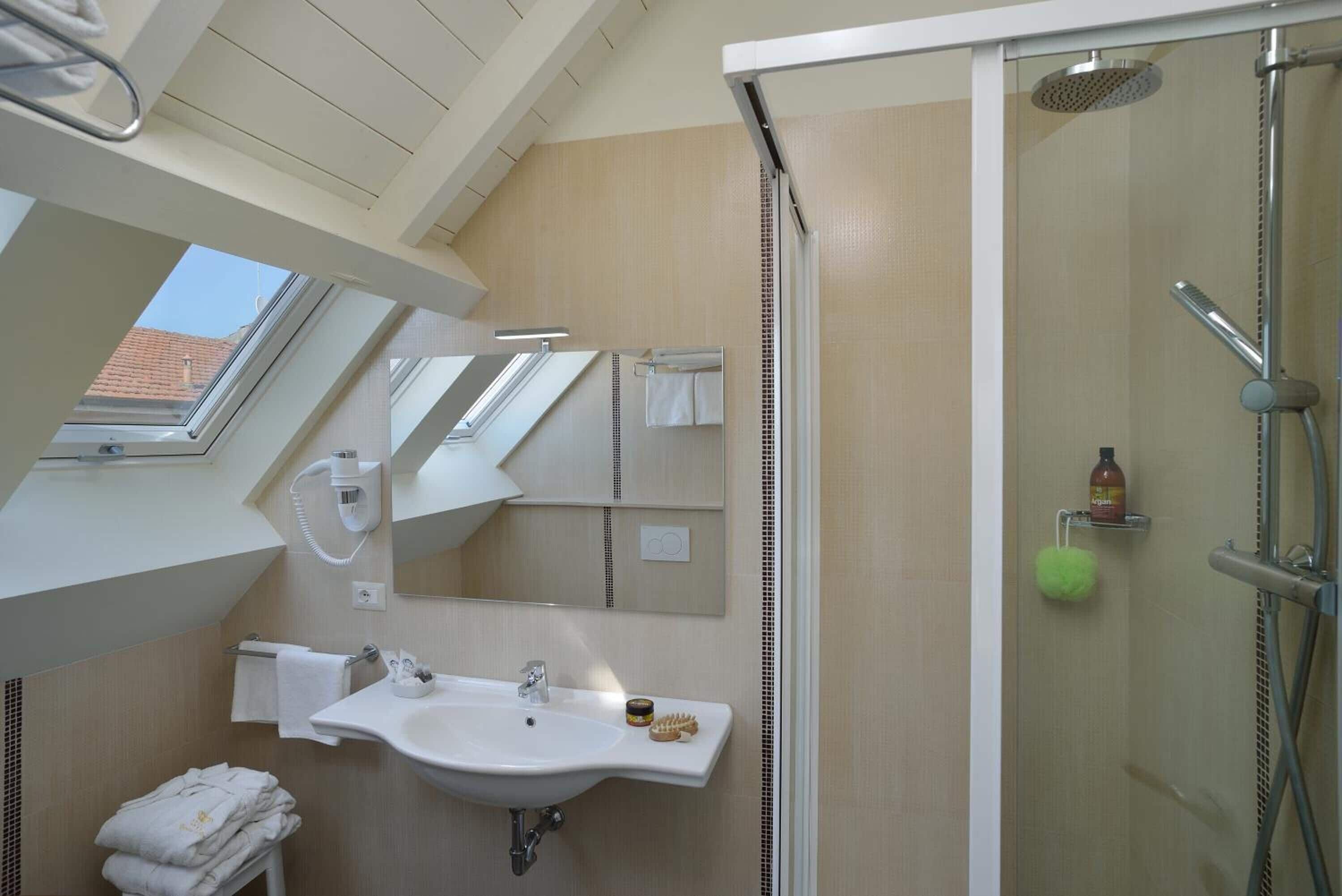 Un baño moderno con tragaluz, un lavabo, un espejo y una ducha.