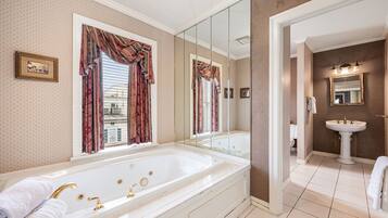 A spacious bathroom with a large bathtub, a separate sink area, and a mirror.