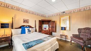 Una habitación de hotel con una cama, una mesita de noche, un armario, una silla y un cuadro en la pared.