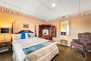 A hotel room with a bed, a nightstand, a dresser, a chair, and a framed picture on the wall. - Waynebrook Inn, Est 1865 (Honey Brook)